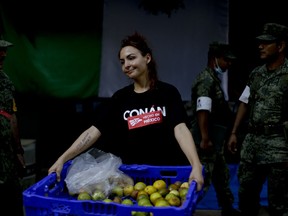 In this Friday, Sept. 22, 2017 photo, Ilya Monforte, a 40-year-old makeup artist, carries oranges for search and rescue workers at a building that collapsed from an earthquake in Mexico City. Monforte, a volunteer in charge of feeding the search and rescue team and military police at the sight following the Sept. 19 magnitude 7.1 earthquake, said: "For the last three days we did not need money, it was like living in socialism. The collective goal during these days was to help others, to take care of them, love them. On each corner you can find people giving." (AP Photo/Natacha Pisarenko)