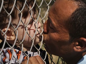 Ammar Hammasho, migrant from Edlib in Syria who lives in Cyprus, kisses one of his four children after they arrived with his mother to a refugees camp in Kokkinotrimithia outside of the capital Nicosia, in the eastern Mediterranean island of Cyprus, on Sunday, Sept. 10, 2017. Cyprus police say a 36-year-old man was arrested Sunday for allegedly driving one of a pair of boats that brought 305 Syrian refugees to the island's northwestern coast. (AP Photo/Petros Karadjias)