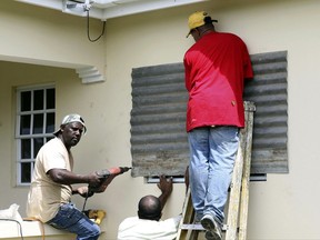 People put up a steel sheet over a window in preparation for Hurricane Irma, in Fort Road, St. John's, Antigua and Barbuda, Tuesday, Sept. 5, 2017.  Irma grew into a dangerous Category 5 storm, the most powerful seen in the Atlantic in over a decade, and roared toward islands in the northeast Caribbean Tuesday on a path that could eventually take it to the United States. (AP Photo/Johnny Jno-Baptiste)