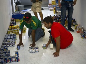 Hospital employees sort donated canned food to deliver to a nearby shelter for hurricane victims, in Catano, Puerto Rico, Thursday, Sept. 28, 2017. The aftermath of the powerful storm has resulted in a near-total shutdown of the U.S. territory's economy that could last for weeks and has many people running seriously low on cash and worrying that it will become even harder to survive on this storm-ravaged island. (AP Photo/Ramon Espinosa)