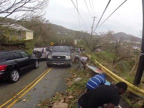 In this image made from video, motorists remove debris caused by Hurricane Irma from the road in St. Thomas, U.S. Virgin Islands, Thursday, Sept. 7, 2017. Hurricane Irma weakened slightly Thursday with sustained winds of 175 mph, according to the National Hurricane Center. The storm boasted 185 mph winds for a more than 24-hour period, making it the strongest storm ever recorded in the Atlantic Ocean. The storm was expected to arrive in Cuba by Friday. It could hit the Florida mainland by late Saturday, according to hurricane center models. (AP Photo/Ian Brown)