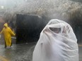 A woman covers herself with a plastic bag as she makes her way to work as Hurricane Maria approaches the coast of Bavaro, Dominican Republic, Wednesday, Sept. 20, 2017