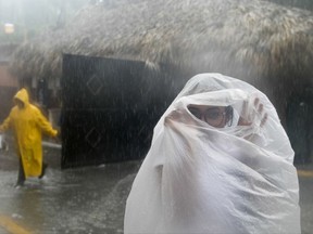 A woman covers herself with a plastic bag as she makes her way to work as Hurricane Maria approaches the coast of Bavaro, Dominican Republic, Wednesday, Sept. 20, 2017. (AP Photo/Tatiana Fernandez)