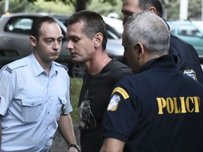 A Russian man identified as Alexander Vinnik, center, is escorted by police officers to the courthouse at the northern Greek city of Thessaloniki on Friday, Sept. 29, 2017. The Russian cybercrime suspect Alexander Vinnik, is wanted in the United States in a $4 billion bitcoin fraud case as Russia wants to extradite him as well on separate fraud charges. (AP Photo/Giannis Papanikos)