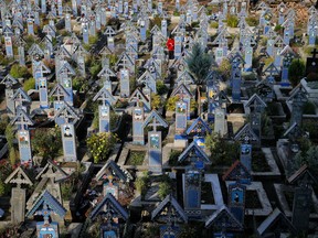 A man stands between the painted crosses in the Merry Cemetery, in Sapanta, northwestern Romania, Sunday, Sept. 10, 2017. The Merry Cemetery is a collection of more than 1,000 vivid Orthodox crosses etched with colorful epitaphs and childlike drawings and, despite its remote location, some 600 kilometers (360 miles) northwest of the Romanian capital, Bucharest, it's one of the country's top tourist attractions. (AP Photo/Vadim Ghirda)