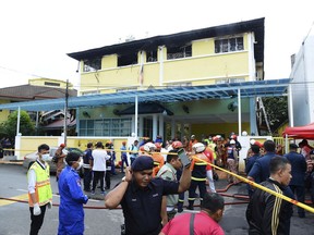 Police and rescue personnel work at an Islamic religious school cordoned off after a fire on the outskirts of Kuala Lumpur  Thursday, Sept. 14, 2017.  A fire department official in Malaysia said a fire at the Islamic religious school has killed 23 people, mostly teenagers.