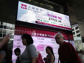 People walk past an electronic board showing Hong Kong share index outside a local bank in Hong Kong, Monday, Sept. 11, 2017. Asian stocks rose strongly Monday after Hurricane Irma weakened and North Korea marked a weekend holiday with celebrations but refrained from launching more missiles, giving investors some relief. (AP Photo/Vincent Yu)