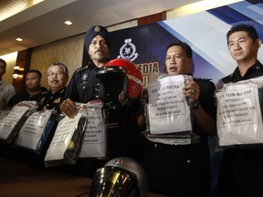 Kuala Lumpur police chief Amar Singh, center and members of his staff display the belongings of detained suspects during a press conference at Kuala Lumpur police headquarters in Kuala Lumpur, Malaysia on Saturday, Sept. 16, 2017. Police have arrested 7 teenage suspects in connection with the fire at a religious school, which claimed the lives of 23 students and teachers on Thursday. (AP Photo/Daniel Chan)