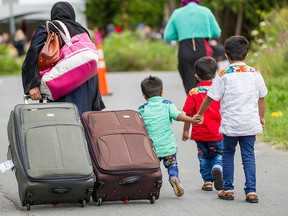 Asylum seekers walk along Roxham Road near Champlain, New York on August 6, 2017, making their way towards the Canada/US border.