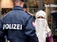 A police officer asks a woman to unveil her face in Zell am See, Austria, on October 1, 2017.  Austria's ban on full-face Islamic veils comes into force following similar measures in other European countries.