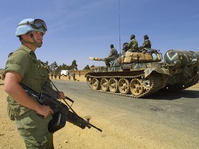 A Canadian United Nation peacekeeper (L) monitors the redeployment of Ethiopian tanks leaving from the Eritrean town of Senafe 20 February 2001.