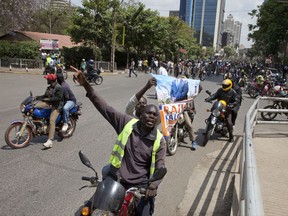 National Super Alliance (NASA) supporters holding poster of opposition leader Raila Odinga ride on a bike as they demonstrate in Nairobi, Kenya, Wednesday Oct. 11, 2017. The protesters are demanding a change of leadership at the country's election commission. The protests took place in the capital Nairobi and the opposition stronghold of Kisumu, in western Kenya, as well as in the coastal city of Mombasa.(AP Photo/Sayyid Abdul Azim)