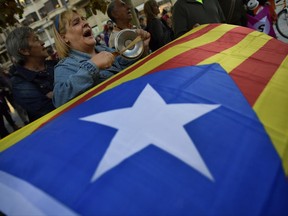 Pro-independence supporters shout slogans in front of the Popular Party headquarters as a "esteleda" or  pro-independence flag is held up, in support of the Catalonia's secession, in Pamplona, northern Spain, Friday, Oct. 6, 2017. (AP Photo/Alvaro Barrientos)