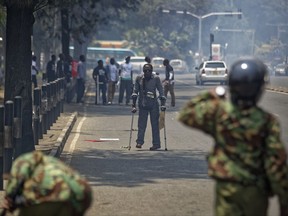 A pedestrian walking with crutches tries to flee as police fire tear gas grenades, at demonstration against police killings of protesters and opposition supporters, in downtown Nairobi, Kenya Thursday, Oct. 19, 2017. Police fired tear gas grenades and rifles in the air to disperse around 20 activists as they were still gathering in Uhuru Park, despite a court order Tuesday that removed the government's ban on demonstrations. (AP Photo/Ben Curtis)
