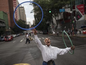Jose Bestilleiro, 83, from Spain, performs for tips at an street intersection in downtown Caracas, Venezuela, Sunday, Oct. 29, 2017. Bestilleiro said he's been performing every day for the past 15 years, and brings in at least 5,000 Bolivars a day, which on the black market is 11 cents and is the price of a cheap "arepa" sandwich. (AP Photo/Rodrigo Abd)