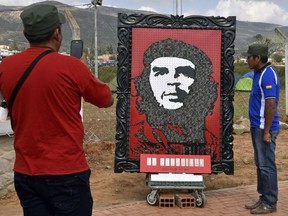 A man takes a picture next to an image of Argentine revolutionary leader Ernesto "Che" Guevara during the celebrations to commemorate the 50th anniversary of his death on October 9, 2017 in Vallegrande municipality, southern Bolivia. The 39-year-old Guevara was captured and executed by a CIA-trained unit of the Bolivian army on October 9, 1967.