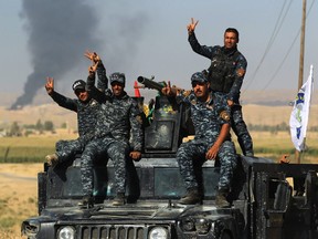 A picture taken on October 17, 2017 shows Iraqi government forces gesturing as the enter the Havana oil field, west of the multi-ethnic northern Iraqi city of Kirkuk.