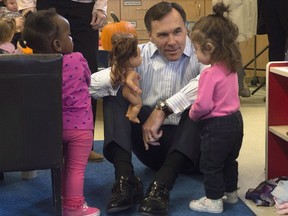 Minister of Finance Bill Morneau sits a plays with two young girls as he tours a daycare centre Wednesday October 25, 2017 in Ottawa. Morneau told reporters he is, in fact, taking a ``balanced'' approach to the country's finances by putting money into the economy while keeping the national debt as a proportion of the overall economy lower than other G-7 countries. THE CANADIAN PRESS/Adrian Wyld