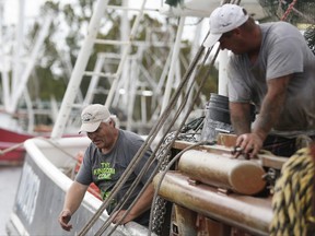 Captain Ashley Johnson, left, and Wayne Hall, right, work to secure the boat "Jeraline" in preparation for Hurricane Nate, expected to make landfall on the Gulf Coast, Saturday, Oct. 7, 2017, in Bayou La Batre, Ala. Storm surge threatened low-lying communities in southeast Louisiana, eastward to the Alabama fishing village of Bayou La Batre. (AP Photo/Brynn Anderson)