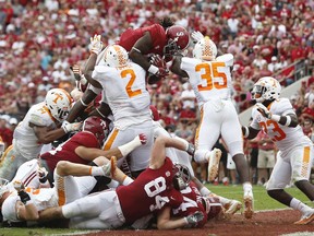 Alabama running back Bo Scarbrough leaps over Tennessee's defensive lineman Shy Tuttle, left, and linebacker Daniel Bituli, right, to score in the first half an NCAA college football game, Saturday, Oct. 21, 2017, in Tuscaloosa, Ala. (AP Photo/Brynn Anderson)