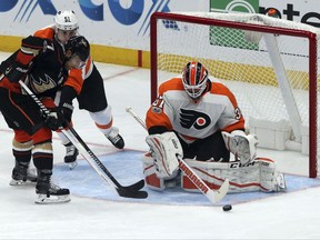 Philadelphia Flyers goalie Brian Elliott (37) guards the goal as Anaheim Ducks left winger Andrew Cogliano (7) presses in the first period of an NHL hockey game in Anaheim, Calif., Saturday, Oct. 7, 2017. (AP Photo/Reed Saxon)