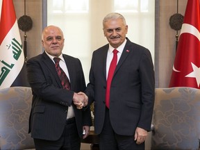 Turkey's Prime Minister Binali Yildirim, right, and Iraqi Prime Minister Haider al- Abadi shake hands during a welcome ceremony in Ankara, Turkey, Wednesday, Oct. 25, 2017. Turkey's President Recep Tayyip Erdogan said his country is prepared to support Iraq's central government export oil through a pipeline to Turkey. Erdogan also said talks were underway on a possible move to close down Turkey's border with Iraq's semi-autonomous Kurdish region, which held a non-binding referendum on independence.(Pool photo via AP)