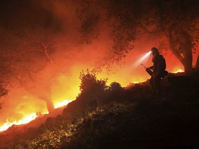 A San Diego Cal Fire firefighter monitors a flare up on a the head of a wildfire (the Southern LNU Complex), off of High Road above the Sonoma Valley, Wednesday Oct. 11, 2017, in Sonoma, Calif. A wind shift caused flames to move quickly up hill and threaten homes in the area. Three days after the fires began, firefighters were still unable to gain control of the blazes that had turned entire Northern California neighborhoods to ash and destroyed thousands of homes and businesses.