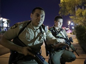 Police officers advise people to take cover near the scene of a shooting near the Mandalay Bay resort and casino on the Las Vegas Strip, Sunday, Oct. 1, 2017, in Las Vegas