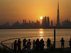 FILE - In this Oct. 7, 2016 file photo, people watch the sunset over the skyline, with Burj Khalifa at right, in Dubai, United Arab Emirates, Monday, Oct. 7, 2016. The coming film "Geostorm" marks just the latest movie in which Western filmmakers put the commercial capital of the United Arab Emirates in its crosshairs. As a mammoth wave from the Persian Gulf rises up to drown fleeing beachgoers and wash over downtown Dubai and the world's tallest building, you can be forgiven for thinking you've seen this all before. (AP Photo/Kamran Jebreili, File)