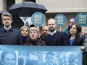 Activists talk to the media as they stage a protest outside a court in Istanbul, Wednesday, Oct. 25, 2017. Eleven human rights activists, including the two local heads of Amnesty International, are going on trial, accused of belonging to and aiding terror groups. Human rights groups say the defendants, who face up to 15 years in prison, have been accused of "trumped up" charges. (AP Photo/Lefteris Pitarakis)