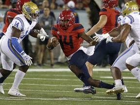 Arizona quarterback Khalil Tate (14) runs for a first down in front of UCLA linebacker Krys Barnes (14) during the first half during an NCAA college football game, Saturday, Oct. 14, 2017, in Tucson, Ariz. (AP Photo/Rick Scuteri)