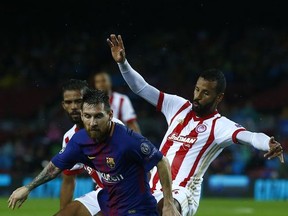 Barcelona's Lionel Messi, front, escapes Olympiakos' Omar Elabdellaoui during the group D Champions League soccer match between FC Barcelona and Olympiakos at the Camp Nou stadium in Barcelona, Spain, Wednesday, Oct. 18, 2017. (AP Photo/Manu Fernandez)