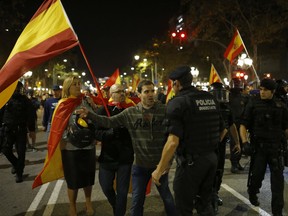 A Catalan policeman talks to an anti-independence supporter as demonstrators are prevented from moving forward during a march against the unilateral declaration of independence approved earlier by the Catalan parliament in downtown Barcelona Friday, Oct. 27, 2017.