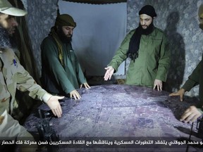 FILE -- This undated file photo, shows Abu Mohammed al-Golani, second right, then leader of Fatah al-Sham Front, in pictures posted by the group, discussing battlefield details with field commanders over a map, in Aleppo, Syria. Russia's military announced Wednesday, Oct. 4, 2017, that it carried out airstrikes in Syria this week that critically wounded al-Golani, the leader of the al-Qaida-linked Levant Liberation Committee and killed 12 other militant commanders. Writing in Arabic  banner reads, "Sheik Abu Mohammed al-Golani inspects military development and discusses them with military commanders as part of the battle for lifting the siege off Aleppo." (Militant UGC via AP, file)