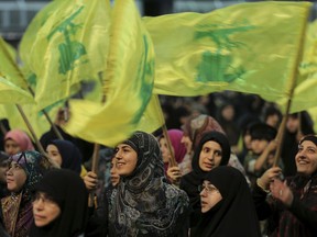 FILE - In this May 20, 2016 file Photo, Hezbollah supporters wave their group flags during a ceremony marking the death of Hezbollah commander Mustafa Badreddine who was killed in an explosion in Damascus last week, in a southern suburb of Beirut, Lebanon. A Hezbollah official says multimillion dollar rewards offered by the Trump administration in return for information leading to the arrest of its operatives are part of ongoing U.S. efforts to "demonize" the group. He also said such false accusations as well as U.S. sanctions imposed on the group will not have any effect on its operational activities. (AP Photo/Hussein Malla, File)