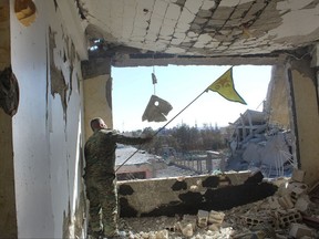In this picture taken on Monday Oct. 16, 2017 and provided by The Syrian Democratic Forces (SDF), a U.S.-backed Syrian Kurdish forces outlet that is consistent with independent AP reporting, shows a Syrian Democratic Forces (SDF) fighter, waves his Kurdish party flag at the front line where they battle against the Islamic State militants, in Raqqa, Syria. The U.S-backed Syrian forces battling the Islamic State group in Syria say Raqqa's national hospital, one of the militants' last holdouts in city has been captured.(Syrian Democratic Forces via AP)