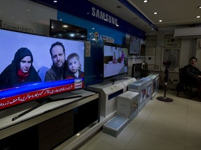 A Pakistani channel broadcasts a report about western couple, seen at a local electronic shop in Islamabad, Pakistan, Thursday, Oct. 12, 2017. An American woman, her Canadian husband and their three young children have been released after years of being held captive by a network with ties to the Taliban, U.S. and Pakistani officials said Thursday. (AP Photo/B.K. Bangash)