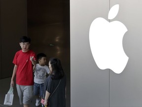 FILE - In this July 30, 2017, file photo, a Chinese family walks out of an Apple store in Beijing. Hundreds of workers protested Wednesday night, Oct. 18, 2017, over bonuses promised through labor brokers who recruited them to work at Jabil Inc.'s Green Point factory, an Apple supplier, in Wuxi city in southern China, according to witnesses. (AP Photo/Andy Wong, File)