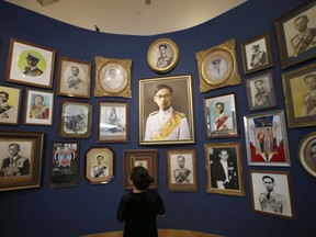In this Sept. 14, 2017, photo, a visitor looks at a photo exhibition of Thailand's late King Bhumibol Adulyadej in Bangkok. As Thailand prepares for King Bhumibol Adulyadej's cremation ceremony Thursday, his image is omnipresent across the country in messages commemorating his life and mourning his death. Photos of a man many Thais loved like a father can be found everywhere from billboards to ATM screens, from full-page tributes in national newspapers to commemorative books in street-side markets, from shrines in shopping malls to exhibits in art galleries. (AP Photo/Sakchai Lalit)