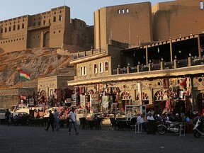 In this Saturday, Oct. 21, 2017 photo, a Kurdish flag waves near almost empty souvenirs shops next to the citadel in central Irbil, Iraq. In September 2017, Iraq's Kurds celebrated their symbolic vote for independence as a historic step toward their decades-old dream of statehood. But instead of moving forward with negotiations toward a smooth divorce from Baghdad, Kurdish politicians have been humiliated with the loss of their most important oil-producing city, Kirkuk, to Iraqi troops. (AP Photo/Khalid Mohammed)