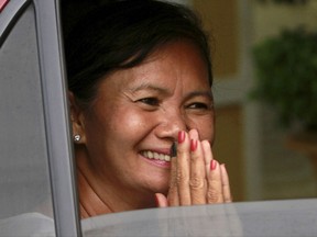 FILE - In this Thursday, Aug. 1, 2013, file photo, Lawmaker from the National Rescue Party Mu Sochua smiles from her car window during a visit to the royal palace in Phnom Penh, Cambodia. Mu Sochua has fled the country after being warned by government officials that she faced arrest for links with the party president's alleged plot to overthrow the government, a senior party official said. (AP Photo/Heng Sinith, File)