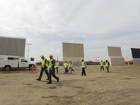 People pass border wall prototypes as they stand near the border with Tijuana, Mexico, Thursday, Oct. 19, 2017, in San Diego.