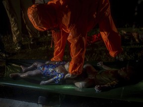 In this Sept. 28, 2017 file photo, a rescue worker places the body of a Rohingya Muslim boy, who died after their boat capsized in the Bay of Bengal as they were crossing over from Myanmar into Bangladesh, onto a stretcher near Inani beach, in Cox's Bazar district, Bangladesh. Of the 80 refugees believed to have been on the boat, only 24 are known to have survived. Police collected 23 corpses from the shore. The rest, mostly children, are missing and presumed to have drowned. They were part of the largest human exodus in Asia since the Vietnam War, a colossal tide of more than 500,000 Rohingya Muslims whose homes had been torched by Buddhist mobs and soldiers. (AP Photo/Dar Yasin, File)