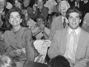 FILE - In this June 6, 1983 file photo, Jacqueline Kennedy Onassis, left, and her son John F. Kennedy Jr., wait to hear a speech by Sen. Edward Kennedy at Brown University in Providence, R.I. Brown University said Friday, Oct. 13, 2017, the college application of John F. Kennedy Jr. that is now up for auction was stolen, and it wants the documents back. The website MomentsInTime.com put an $85,000 price tag on a collection of documents, including Kennedy's application and letters from his mother discussing his time at Brown. (AP Photo/Peter Southwick, File)