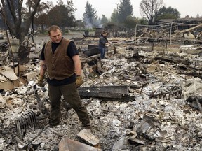 Luke Baier, left, and his wife Gina Baier look through the remains of their home in the Coffey Park area of Santa Rosa, Calif., on Tuesday, Oct. 10, 2017. An onslaught of wildfires across a wide swath of Northern California broke out almost simultaneously then grew exponentially, swallowing up properties from wineries to trailer parks and tearing through both tiny rural towns and urban subdivisions. (AP Photo/Ben Margot)