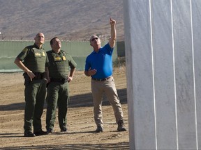 Jim O'Loughlin, site manager, right, explains some of the features of one of the border wall prototype to Ronald Vitiello, U.S. Customs and Border Protection's acting deputy commissioner, left, and Roy Villarreal.