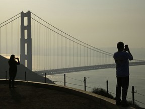 People take pictures of the Golden Gate Bridge as smoke from wildfires covers the San Francisco skyline Tuesday, Oct. 10, 2017, in this view near Sausalito, Calif. An onslaught of wildfires across a wide swath of Northern California broke out almost simultaneously then grew exponentially, swallowing up properties from wineries to trailer parks and tearing through both tiny rural towns and urban subdivisions. (AP Photo/Eric Risberg)