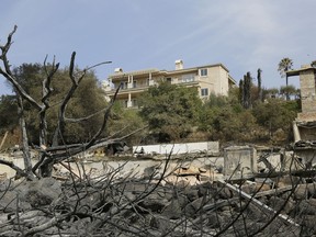 A house stands intact above one that was destroyed by wildfire near Atlas Peak Road, Monday, Oct. 16, 2017, in Napa, Calif. State and local officials say they are trying to get people back into their homes, but they cautioned that it could take days and even weeks for neighborhoods hard hit by Northern California wildfires. (AP Photo/Eric Risberg)