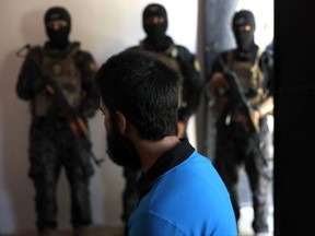 In this file picture taken on Friday, July 21, 2017, Kurdish soldiers from the Anti-Terrorism Units, background, stand in front a Turkish suspected Islamic State member, Onur, at a security center, in Kobani, Syria.