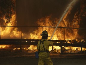 FILE - In this Oct. 9, 2017 file photo, a firefighter sprays a hose into a Keysight Technologies building in Santa Rosa, Calif. The Santa Rosa Press Democrat reported that more than 100 boxes of letters and other materials from tech pioneers William Hewlett and David Packard burned in the fires. Electronics firm Keysight Technologies had acquired the archives through spinoffs, and the archives were stored at its offices in Santa Rosa. (AP Photo/Jeff Chiu, file)